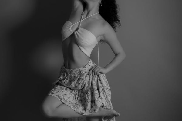 A person performing a flowing exercise movement in a minimalist studio.